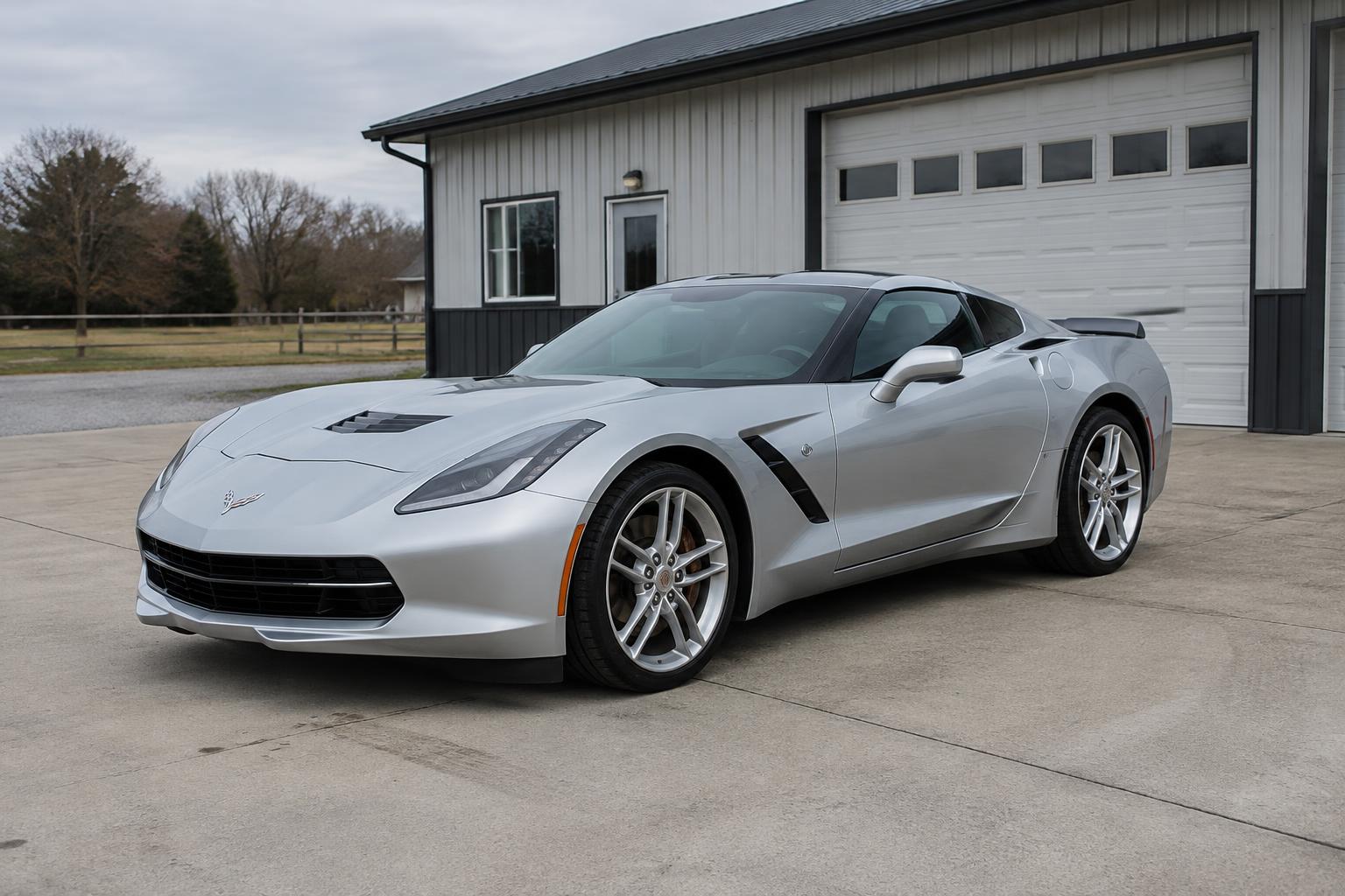 Silver Corvette coupe parked outside an automotive garage
